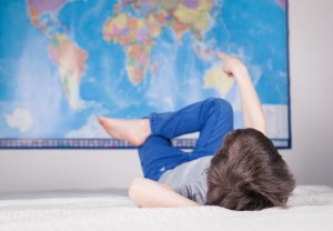 Small boy pointing at a map of the world